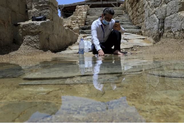 O cristão sírio Zuhair Al-Sahawi mergulha uma mão na água do local de batismo Betânia do Além-Jordão, na margem oriental do Rio Jordão, na Jordânia — Foto: Raad Adayleh/AP